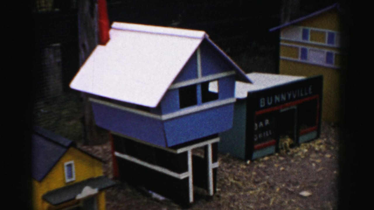 Blue miniature building with white roof beside a dark 'Bunnyville' sign showing partial additional text; yellow building at right; possibly a 1950s Catskill, New York tourist display.
