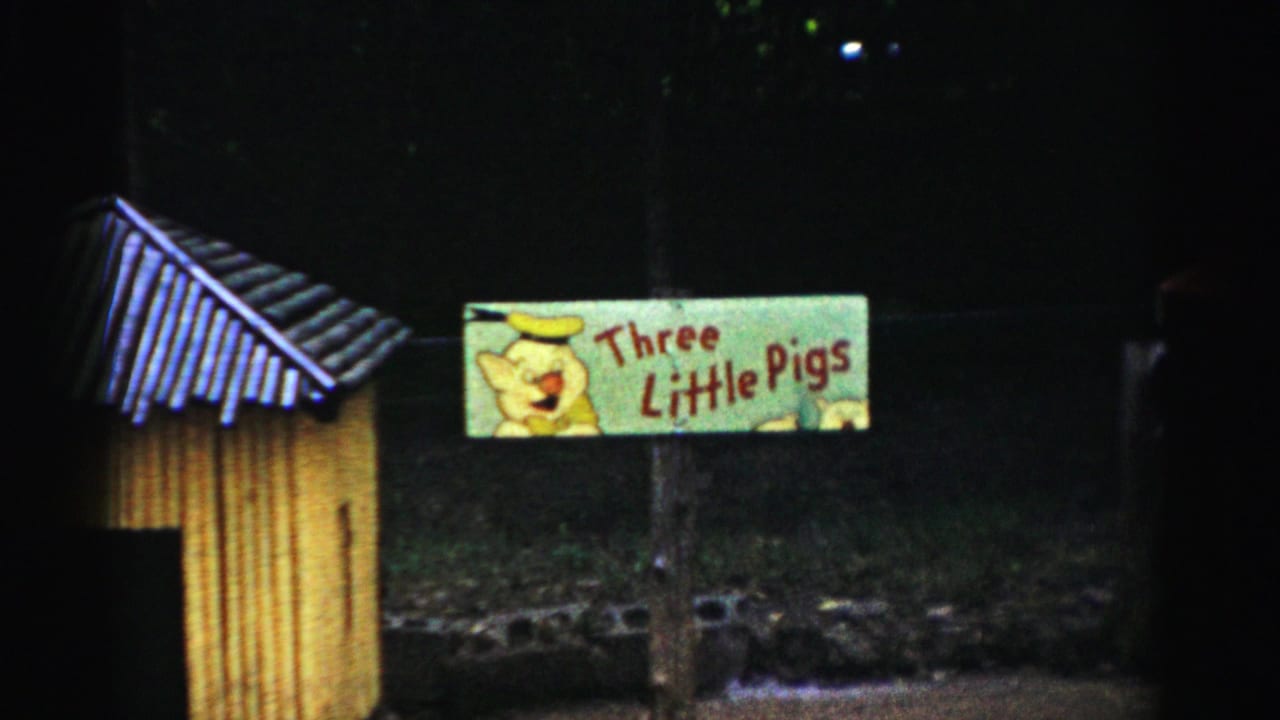 Green 'Three Little Pigs' sign with cartoon pig and red lettering on a yellow wooden enclosure, circa 1957 Catskill, New York, 8mm film.