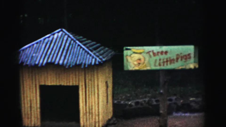 Yellow animal enclosure with blue peaked roof and Three Little Pigs sign centered in frame, consistent with 1950s Catskill attraction footage.