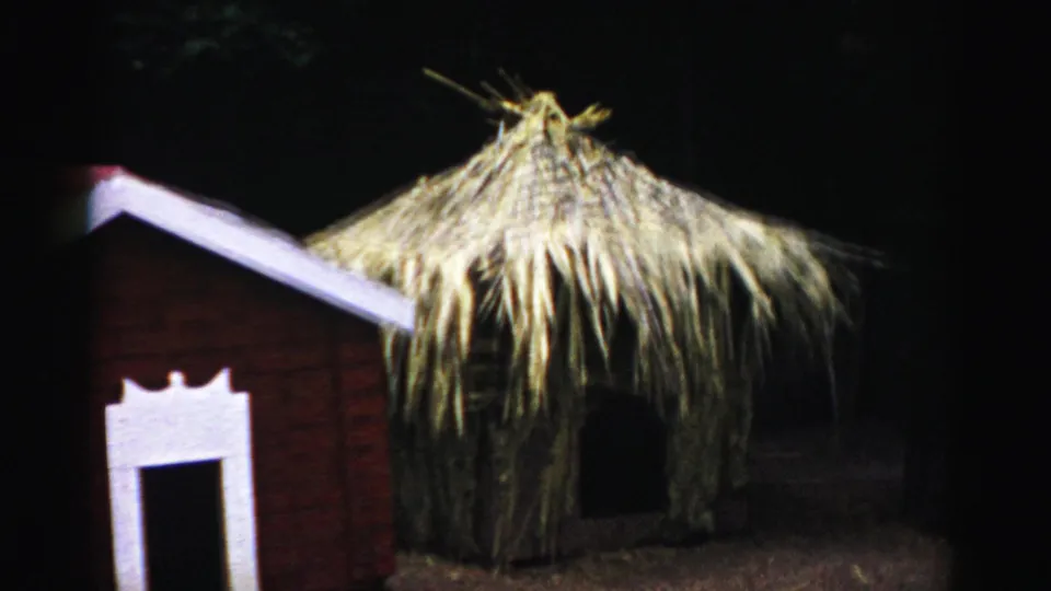 Thatched-roof straw hut prop alongside brick miniature house at Three Little Pigs themed attraction, Catskill, New York, circa 1957