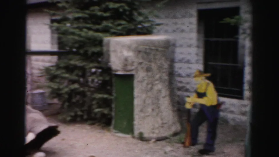 Man in yellow shirt and wide-brimmed hat at stone enclosure building, Catskill area, New York, circa 1957, 8mm home movie footage.