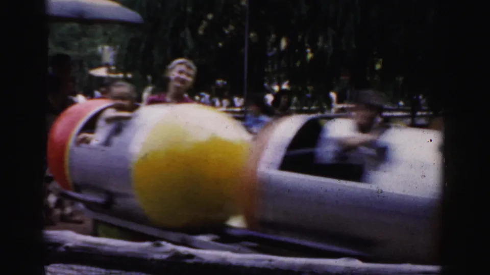 Children on a small amusement ride with colorful cars at what appears to be a fairground or animal park, Catskill area, New York, circa 1957, 8mm film.