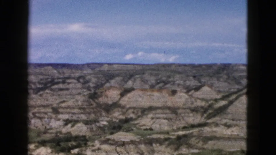 8mm footage circa 1958 showing Wyoming eroded rock formations receding to the horizon; broad sky occupies the upper half of the frame.