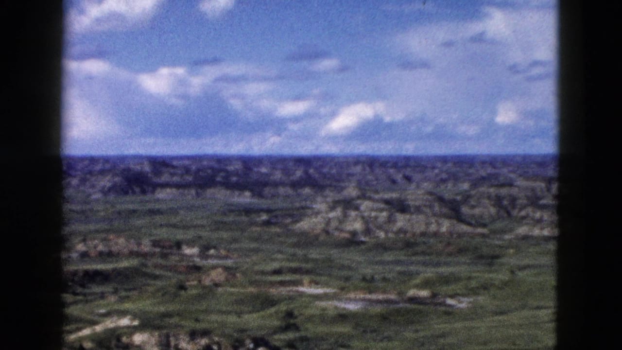 Mid-pan 8mm frame of rocky eroded formations and green valleys, Yellowstone/Wyoming region, circa 1958.