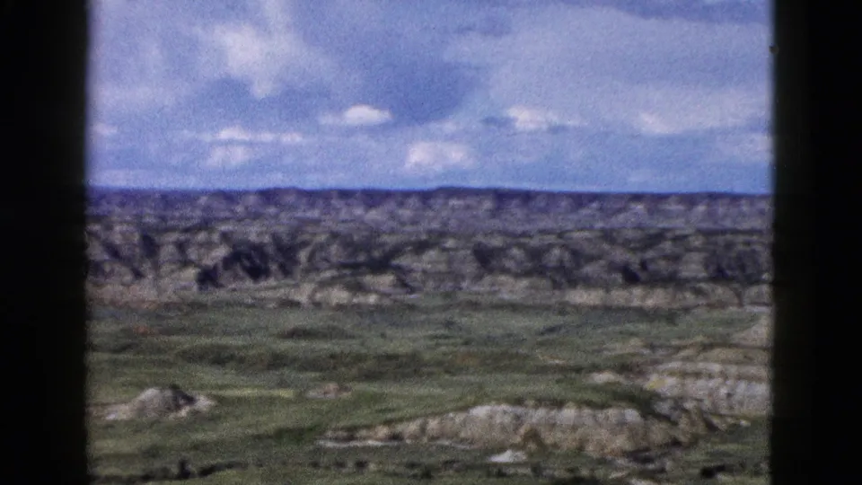 8mm film frame of rugged eroded terrain and valleys under cumulus clouds, Yellowstone/Wyoming region, circa 1958.