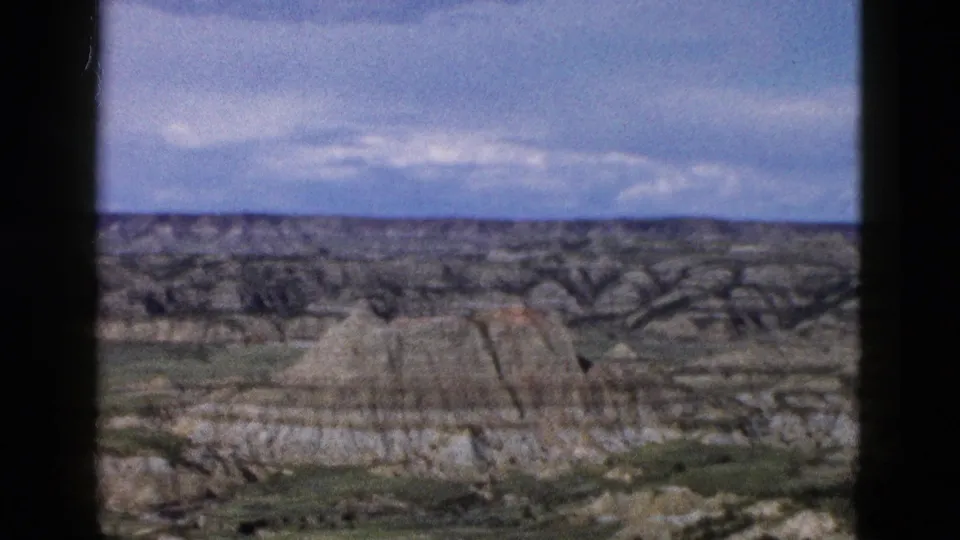 8mm archival frame c.1958 showing a pan across layered eroded buttes and arid terrain attributed to Wyoming.