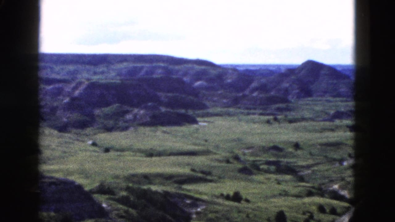 8mm home-movie pan across eroded Wyoming ridgelines; a rocky butte rises on the right horizon, Yellowstone area, circa 1958.