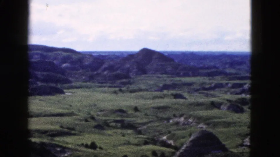8mm color wide shot of scattered conical buttes across an open green valley, Yellowstone area Wyoming, circa 1958.