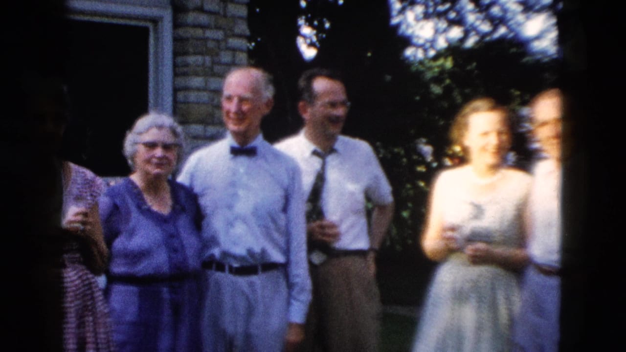 1950s outdoor group portrait; adults in mid-century dress shirts and full-skirted dresses posed near a brick building, attributed to Wyoming, 1958.