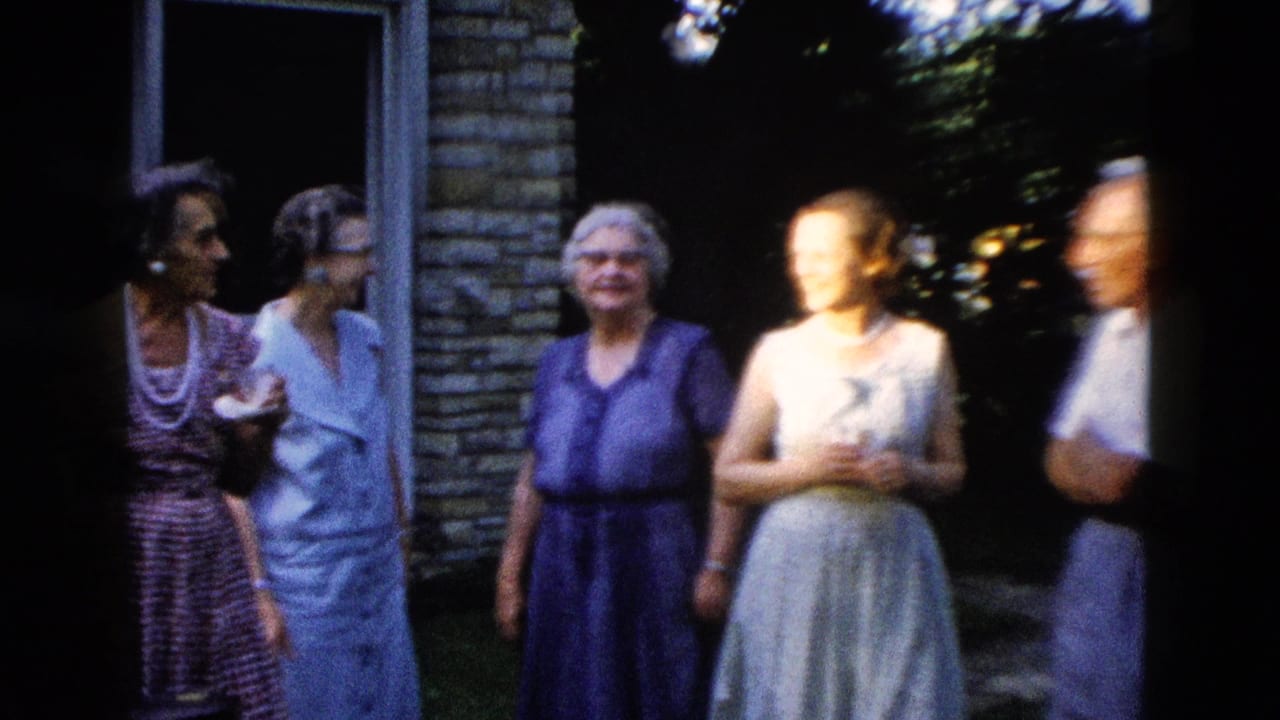 Older women in 1950s dresses and one man gathered outdoors near a light brick building, with motion blur on some figures, circa 1958.