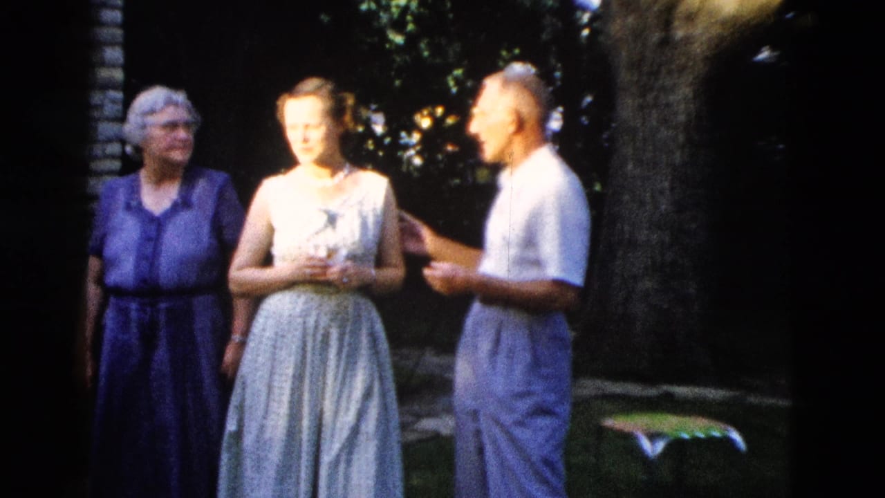 c. 1958 outdoor gathering in Wyoming: elderly woman in purple dress, young woman in light sleeveless dress with pearl necklace, and man in white shirt talking beneath a shade tree.