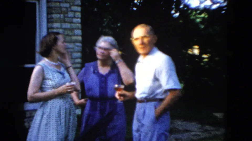 Two women in 1950s summer dresses and a man in a white shirt conversing outdoors, consistent with metadata placing this clip in Wyoming, USA, circa 1958.