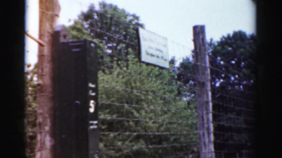A closer visitor view shows the enclosure fence, a small sign, and a wooden post at the Catskill Game Farm in 1957 8mm footage.