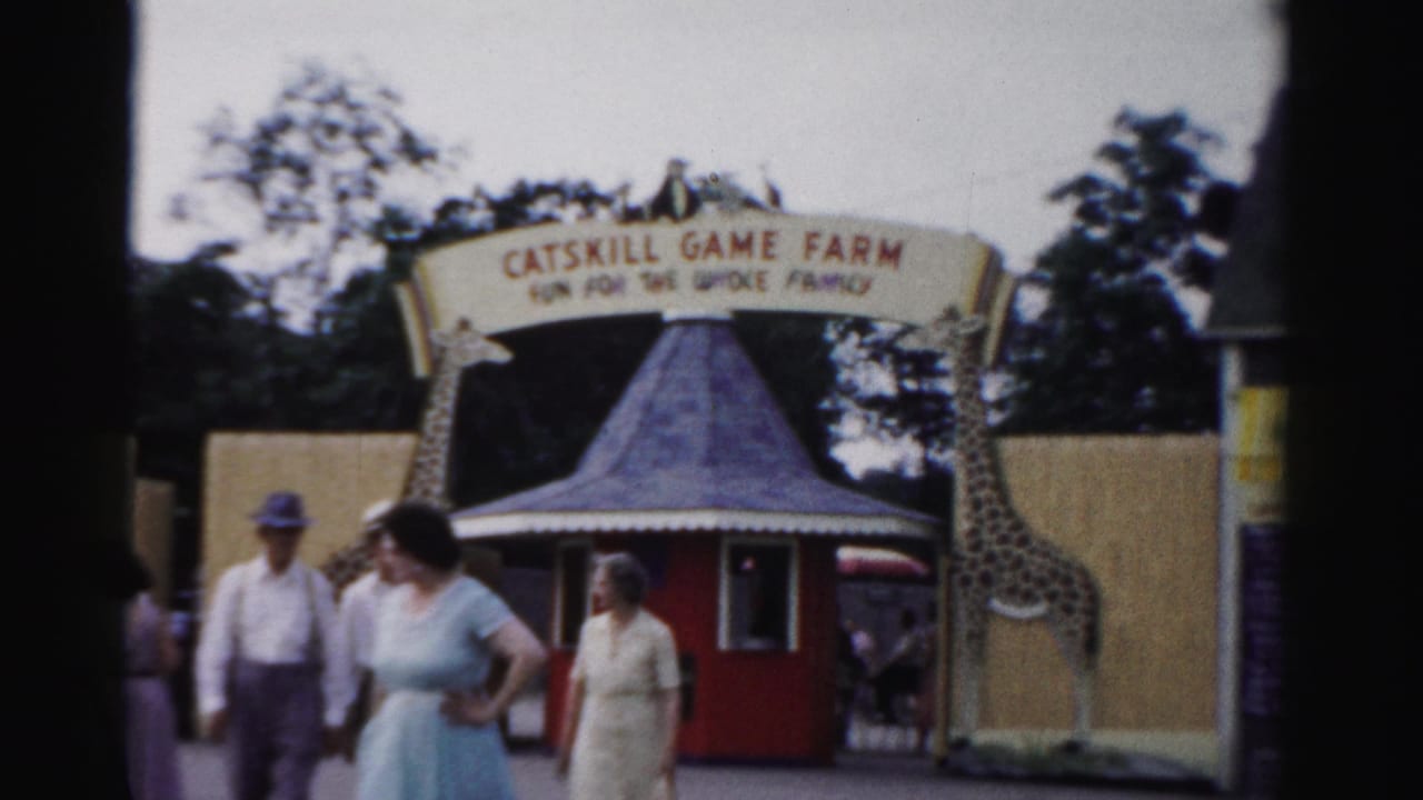 People stand and walk near the Catskill Game Farm entrance and red booth.