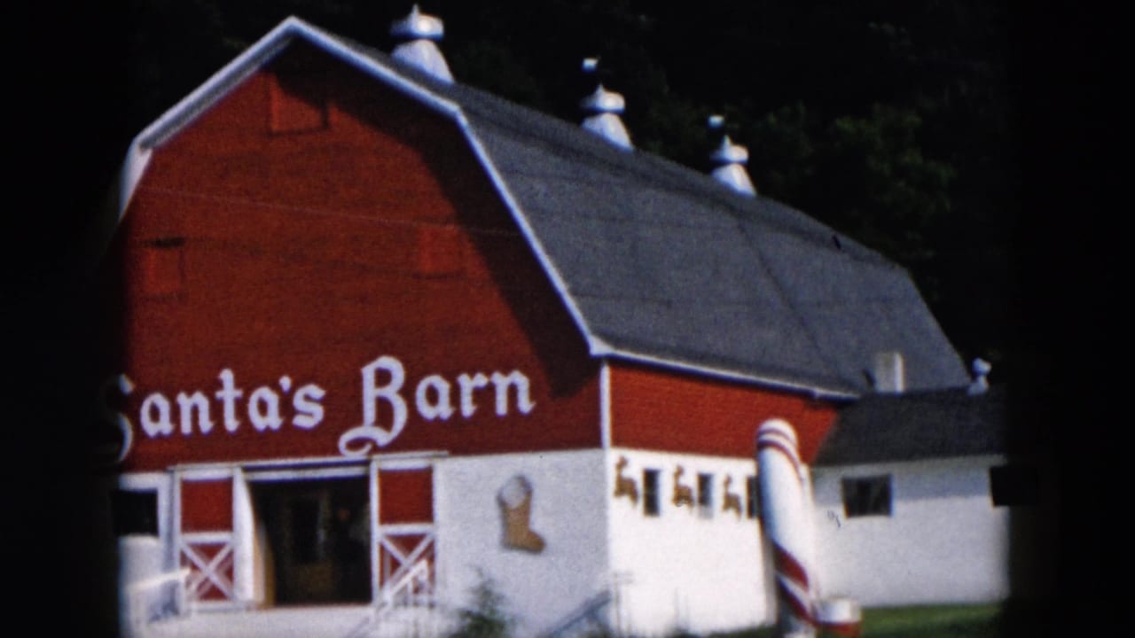 1957 Hicksville, New York 8mm frame showing a red and white Santa's Barn facade with a candy cane decoration and ramp.