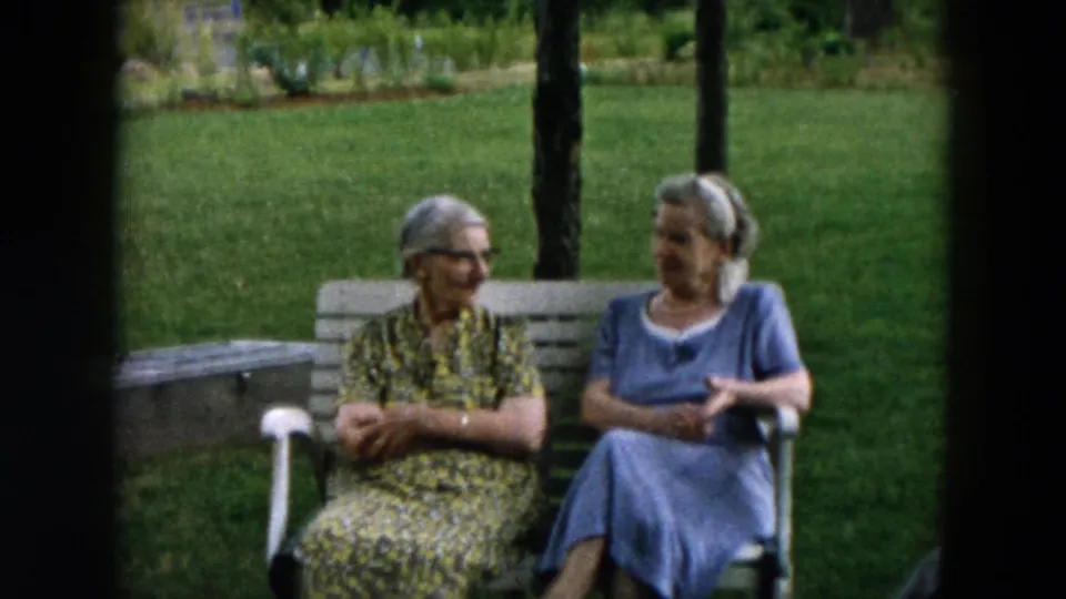 Two older women continue their conversation in a 1957 Hicksville outdoor home-movie scene.
