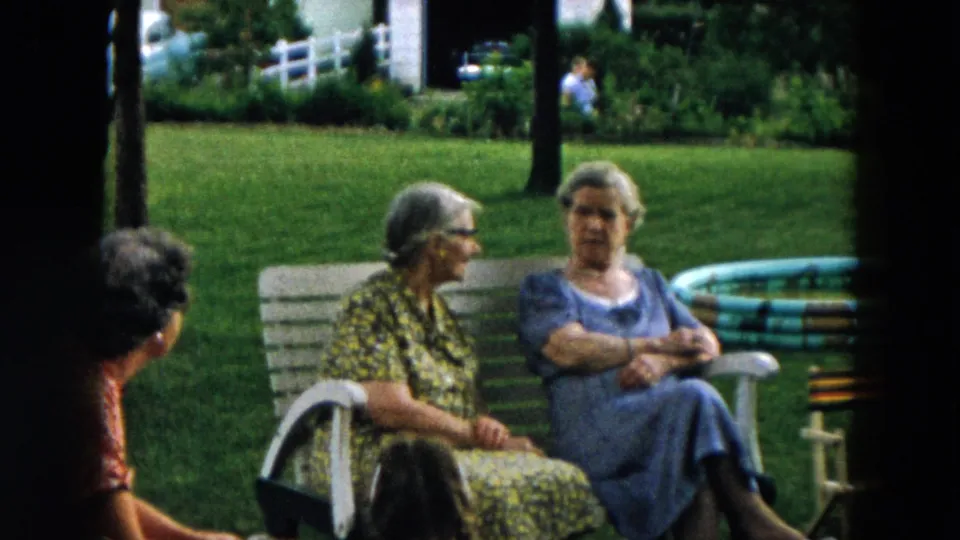 In Hicksville, New York in 1957, elderly women sit near a white yard bench during a backyard conversation.