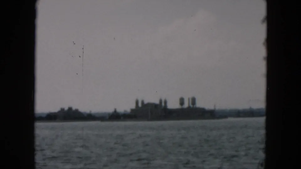 The camera continues past a distant 1957 shoreline view, with buildings and vertical structures softened by motion and haze.