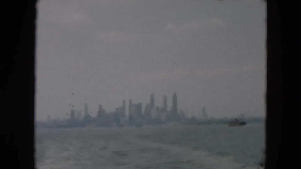 Misty 1957 8mm harbor view toward a distant Manhattan skyline under a gray sky.