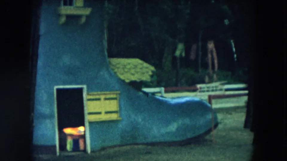 1957 Hicksville footage shows the boot-shaped playhouse from a slightly different angle, with its dark doorway, curved blue wall, and wooded surroundings.