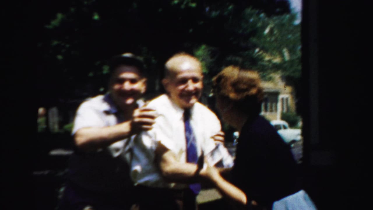In Normal, Illinois, in 1957, two men and a woman appear to laugh and nudge each other outside a suburban house.