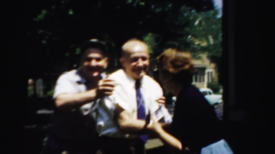 In Normal, Illinois, in 1957, two men and a woman appear to laugh and nudge each other outside a suburban house.
