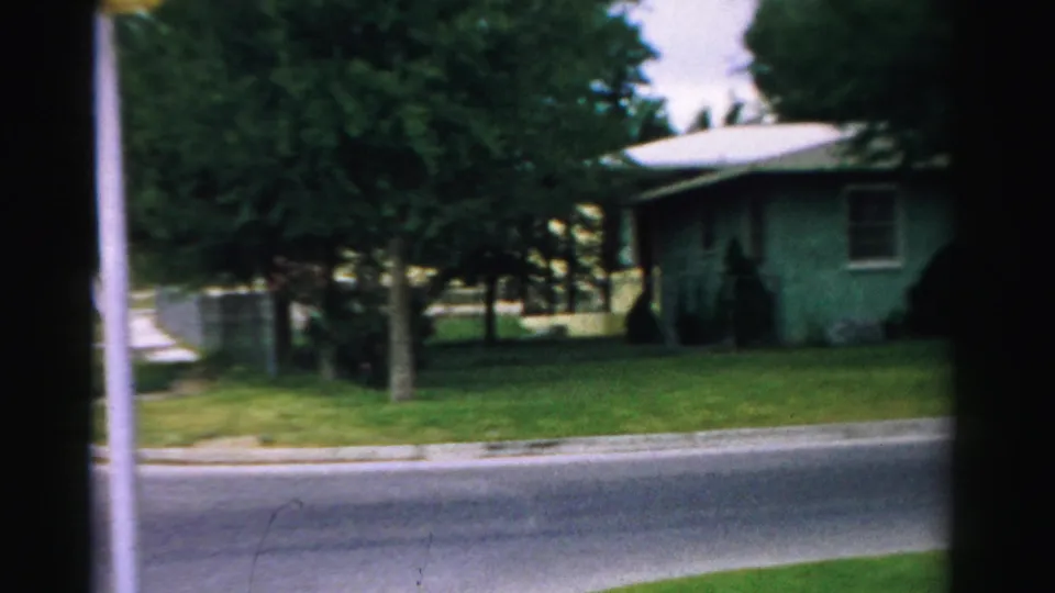 1957 Normal, Illinois residential view with a green single-story house, trees, lawn, sidewalk, and street foreground.