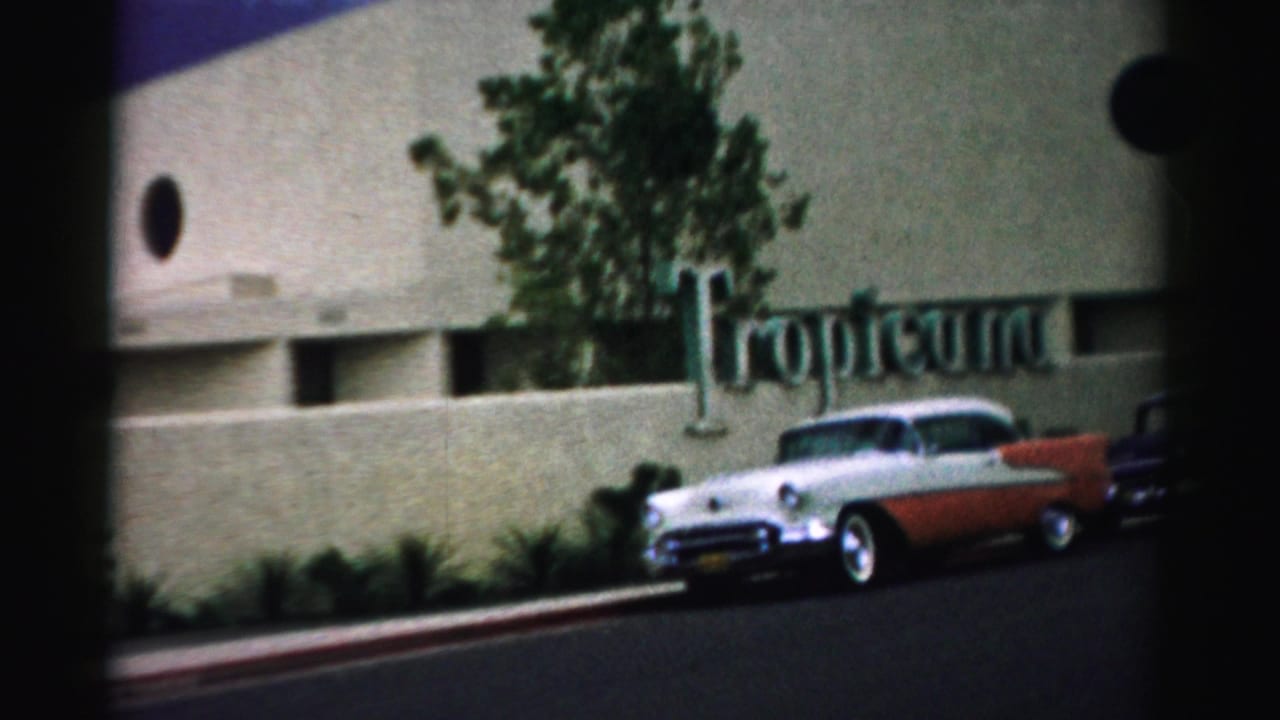 The Tropicana frontage appears from across the street, with mid-century cars and landscaping in front of the facade.