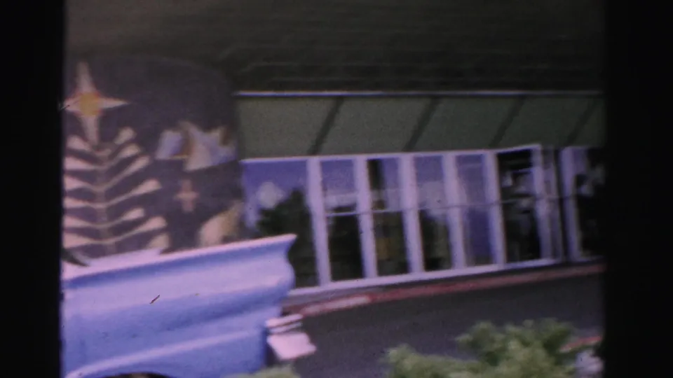 Las Vegas exterior view shifts to glass doors and windows, with a 1950s car tail fin partly visible in the foreground.