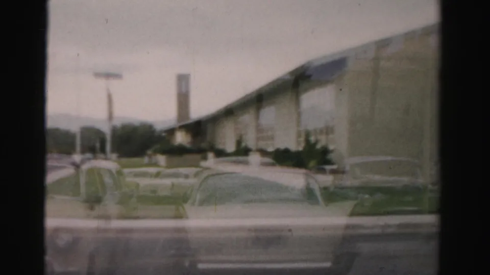 Soft 8mm view of a long low church building in Las Vegas, with parked cars, a roadside sign area, and landscaping in front.