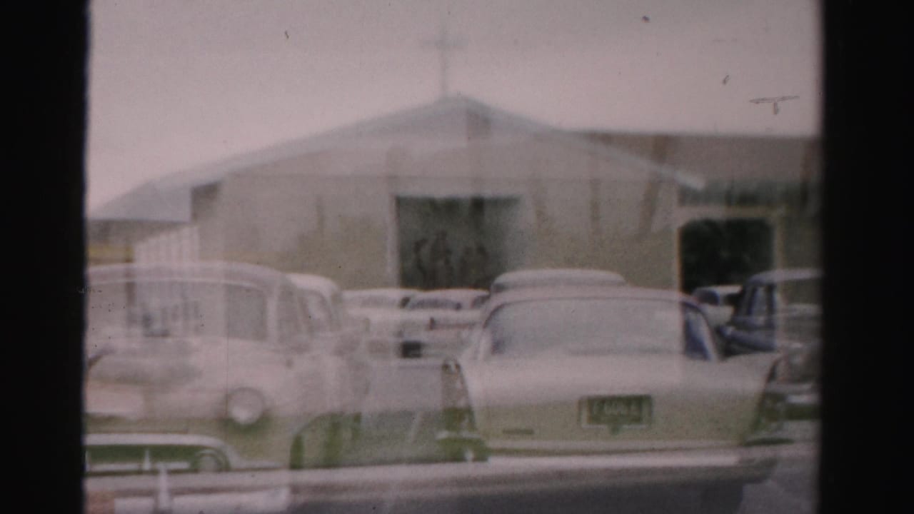 Beige church-like building behind parked 1950s cars on a Las Vegas street.