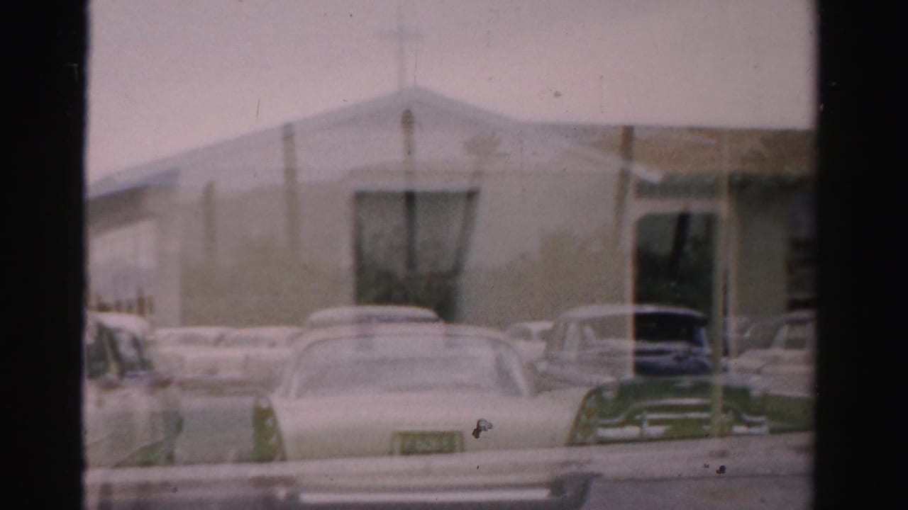 Parked classic cars line the street outside a pale low-rise building.