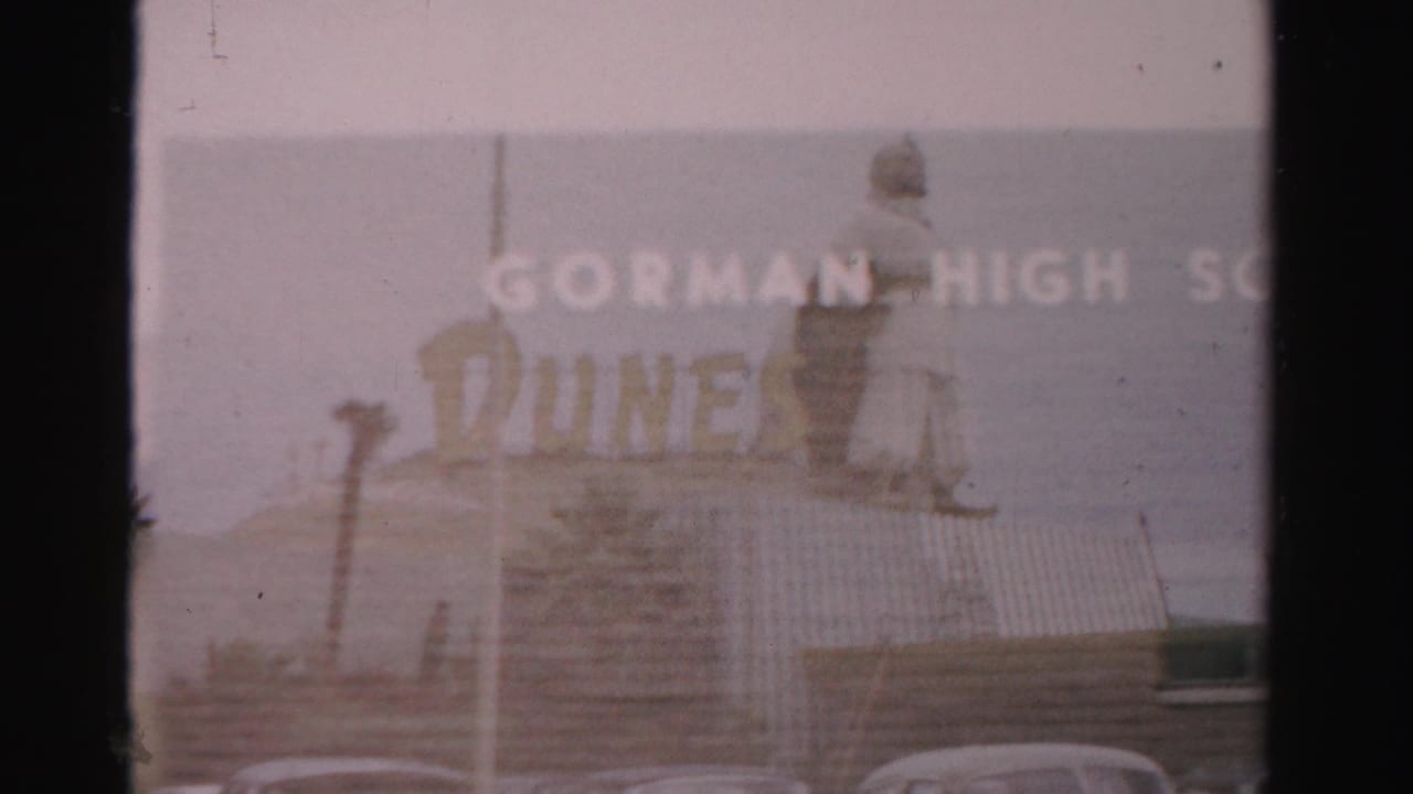 Gorman High School lettering appears above a low building with cars at the bottom of the frame.