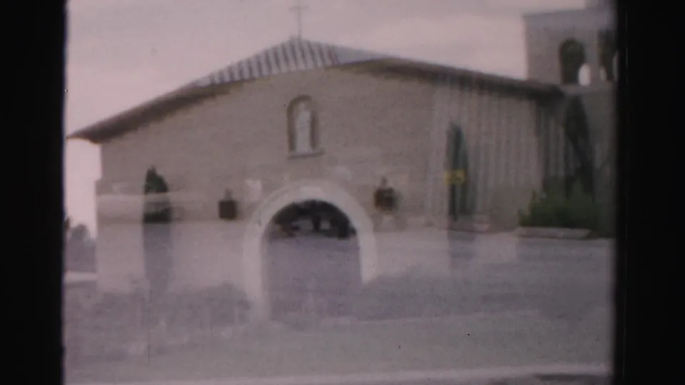 1957 Las Vegas home-movie frame showing a stucco building with an arched entrance and nearby vertical architectural detail.