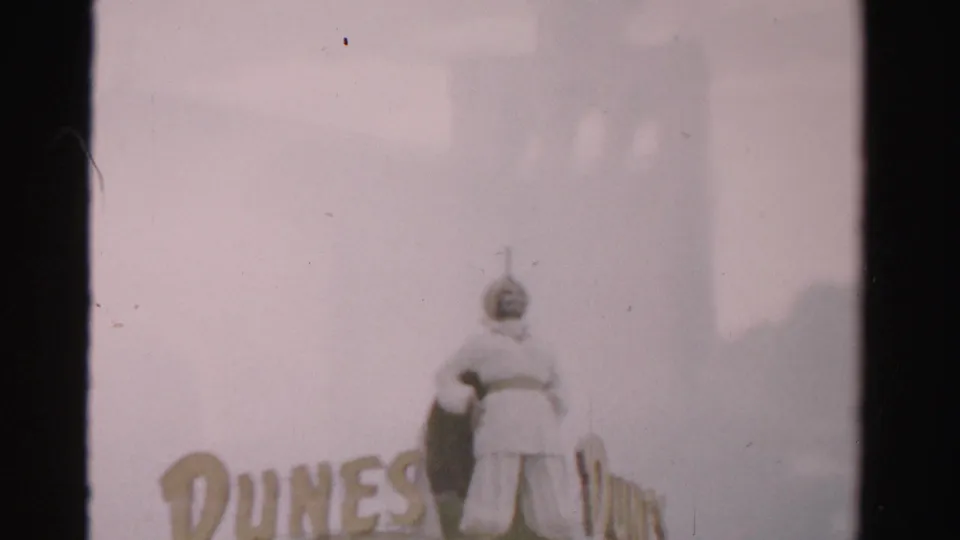 Faded 1957 Las Vegas frame showing a Dunes sign figure and large DUNES lettering, partly obscured by exposure haze.