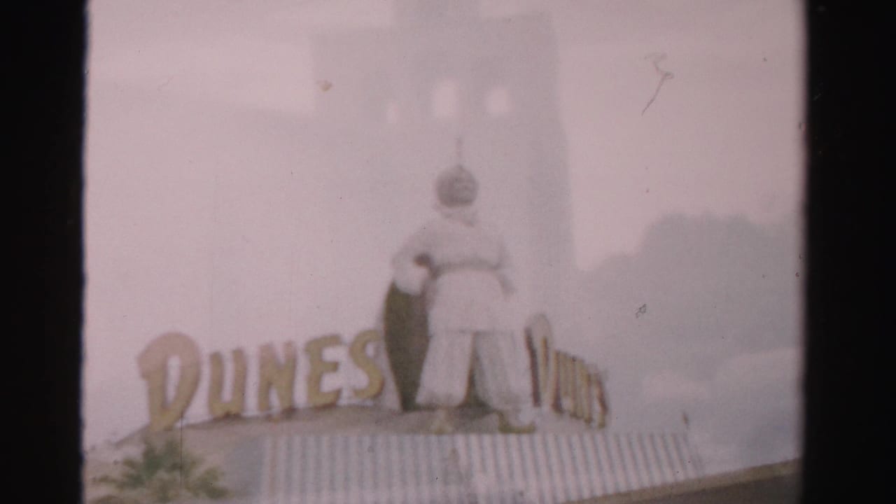 Dunes sign and rooftop figure framed beside a dark film divider.