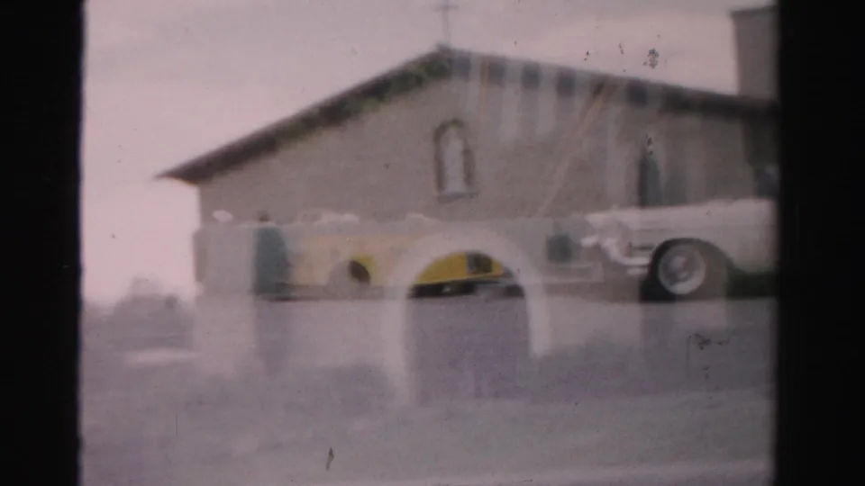 1957 Las Vegas street view showing a stucco building, arched windows, a yellow convertible, and a white sedan.