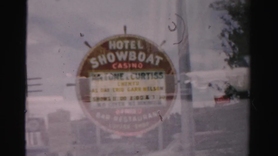 1957 Las Vegas home-movie frame showing the Hotel Showboat Casino sign with event lettering and street details.