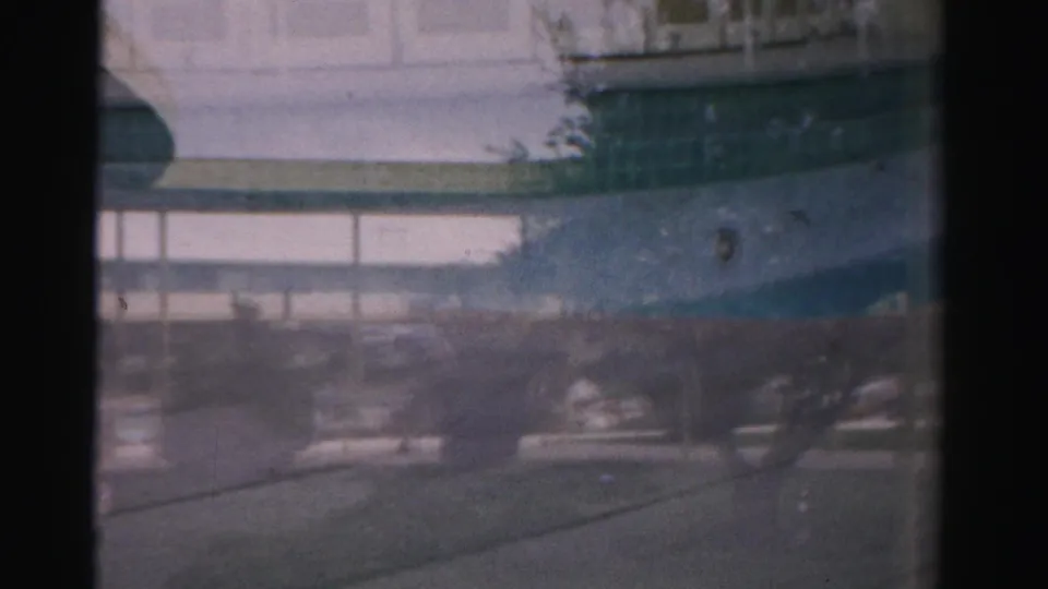 The final frame holds on a soft lower street view through glass, with vehicle bodywork, reflections, and window framing from the 1957 Las Vegas scene.