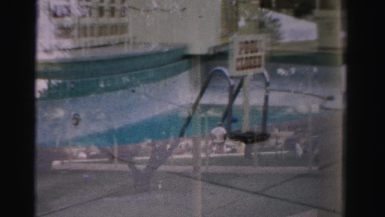 Pool edge with metal ladders, closed sign, deck, and distant seating.