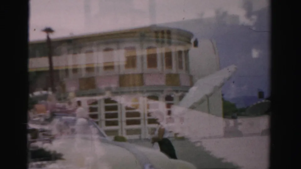 Las Vegas 1957 frame showing a riverboat-like facade, exterior stairs, and poolside figures blended by the cross-fade.