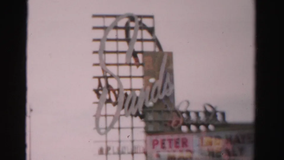 1957 Las Vegas frame showing the Sands sign above a marquee with partially readable performer names.
