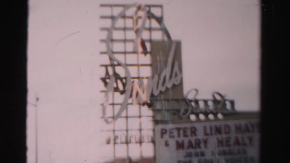 1957 Las Vegas 8mm frame of the Sands sign and marquee, with partial names visible and a dark film edge at right.