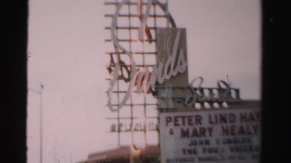 1957 Las Vegas home-movie frame showing the Sands theater sign and marquee, with Peter Lind Hayes and Mary Healy partly legible.