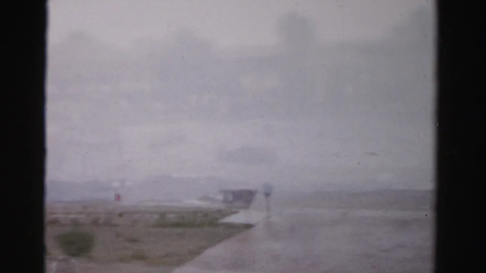 The final 1957 Las Vegas-area frame is largely hazy, showing shallow water, wet sand, a low distant structure, and strong 8mm frame borders.