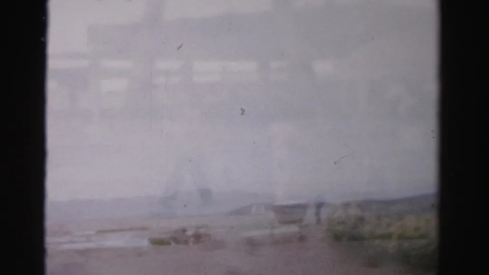 Faded 1957 Las Vegas home-movie frame showing a hazy outdoor walkway and patio area with distant people.