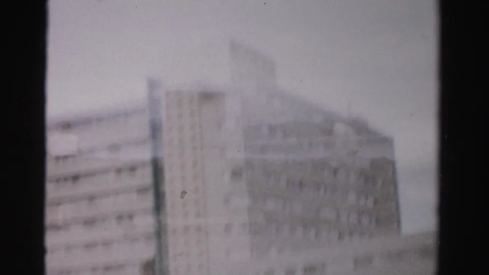 1957 Las Vegas frame with a multi-story building facade and roadside structures partially obscured by a dark vertical divider.
