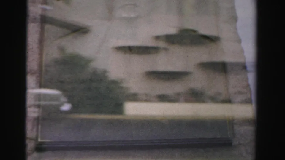 1957 Las Vegas home-movie frame showing the Royal Nevada facade area with decorative wall forms, shrubs, curb, and street foreground.