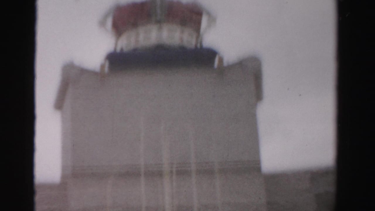 1957 Las Vegas frame showing a beige crown-topped structure beyond a dark interior window divider under a pale sky.