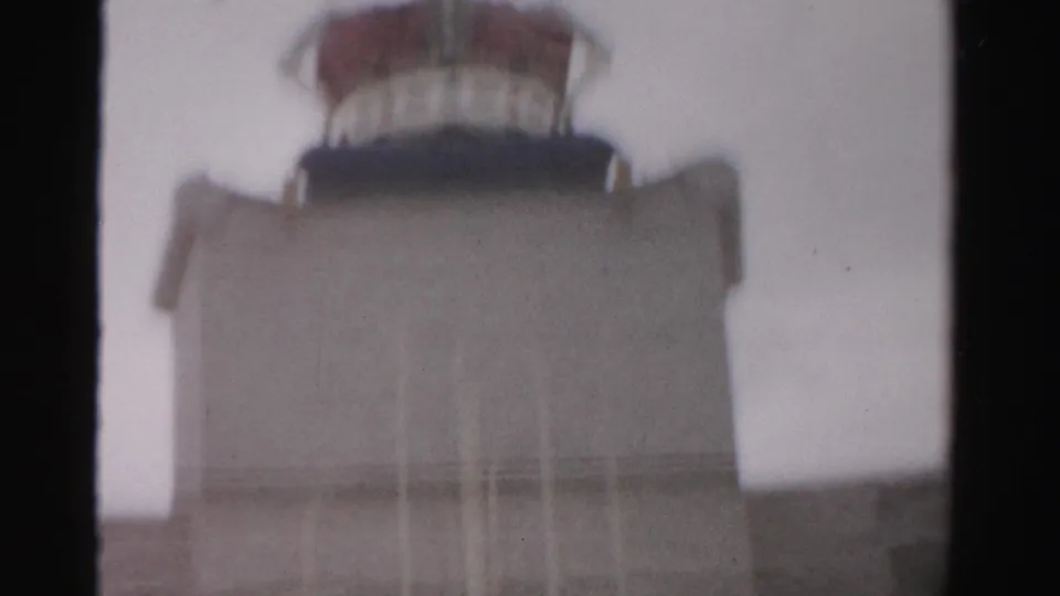 1957 Las Vegas frame showing a beige crown-topped structure beyond a dark interior window divider under a pale sky.